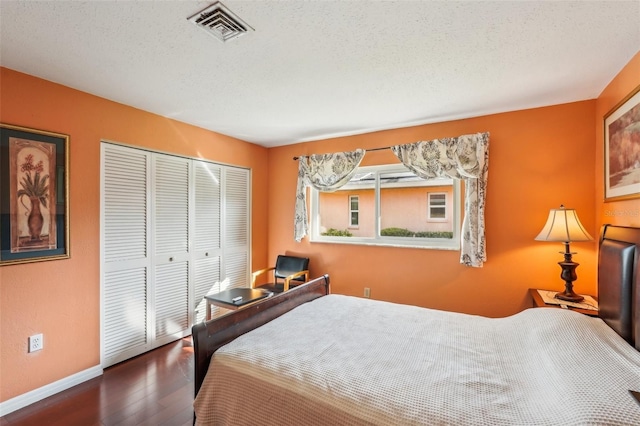 bedroom featuring dark hardwood / wood-style flooring, a textured ceiling, and a closet