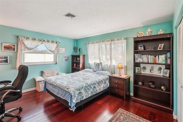 bedroom with dark hardwood / wood-style flooring, a textured ceiling, and multiple windows