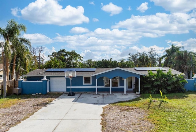 ranch-style home featuring a garage, a front lawn, solar panels, and covered porch