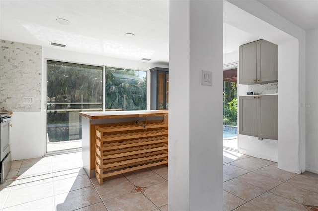 kitchen featuring decorative backsplash, a wealth of natural light, light tile patterned floors, and gray cabinets