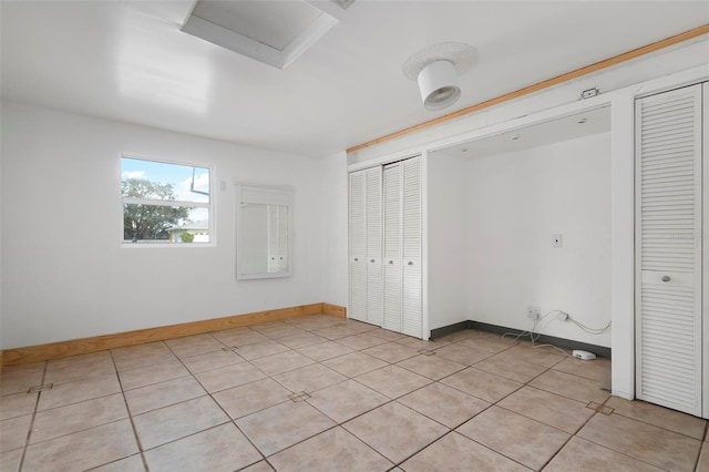 unfurnished bedroom featuring light tile patterned flooring and two closets