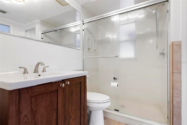 bathroom featuring a shower with door, toilet, vanity, and tile patterned flooring