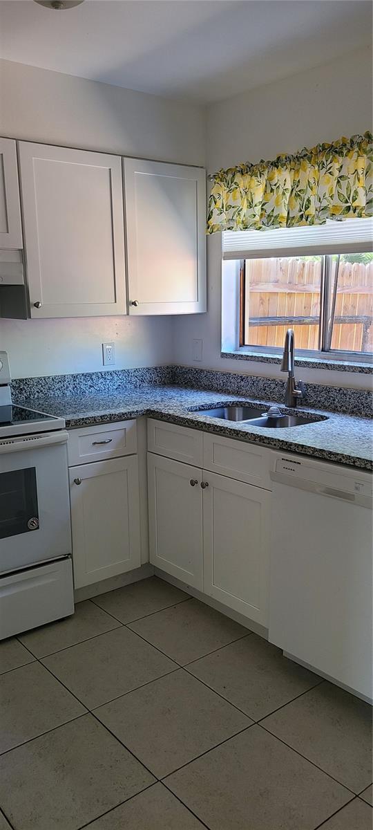 kitchen featuring white cabinets, white appliances, light tile patterned flooring, and sink