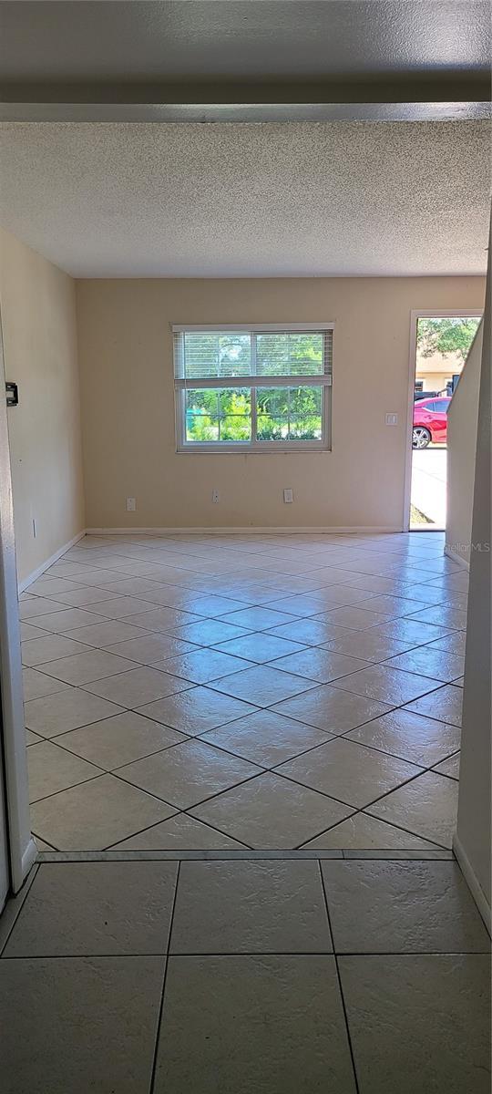 tiled empty room featuring a textured ceiling