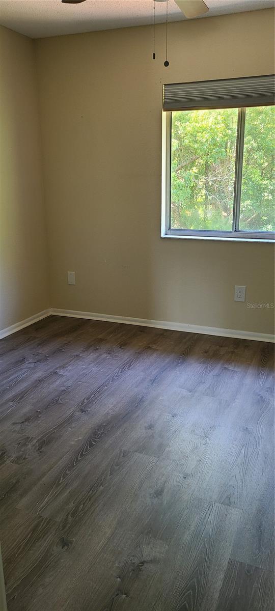 spare room with a textured ceiling, dark hardwood / wood-style floors, and ceiling fan