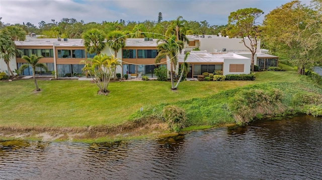 rear view of house with a lawn and a water view