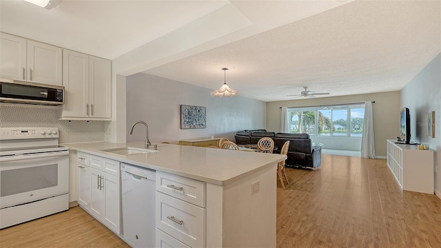 kitchen with white cabinets, kitchen peninsula, white appliances, and sink