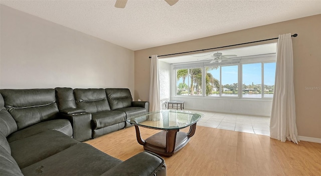 living room featuring light wood-type flooring, a textured ceiling, and ceiling fan