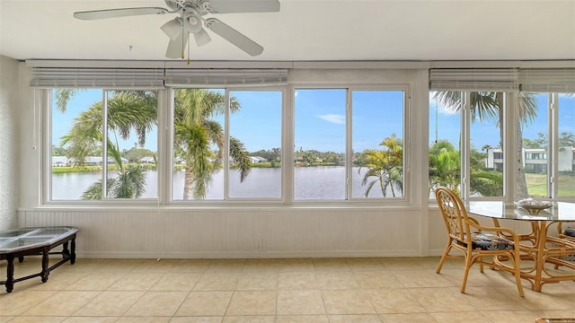 sunroom / solarium featuring a water view, plenty of natural light, and ceiling fan