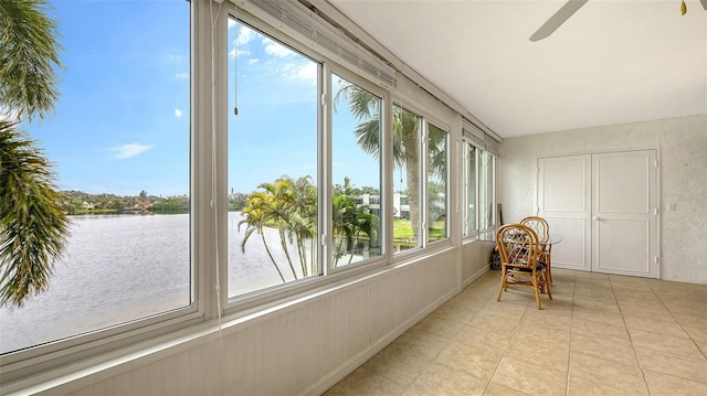 sunroom / solarium featuring ceiling fan and a water view