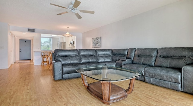 living room featuring a textured ceiling, light hardwood / wood-style flooring, and ceiling fan