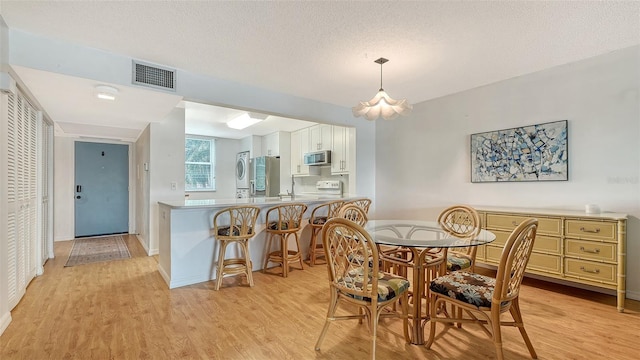 dining area with a textured ceiling and light hardwood / wood-style flooring