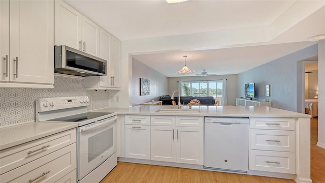 kitchen featuring white appliances, white cabinets, sink, tasteful backsplash, and kitchen peninsula