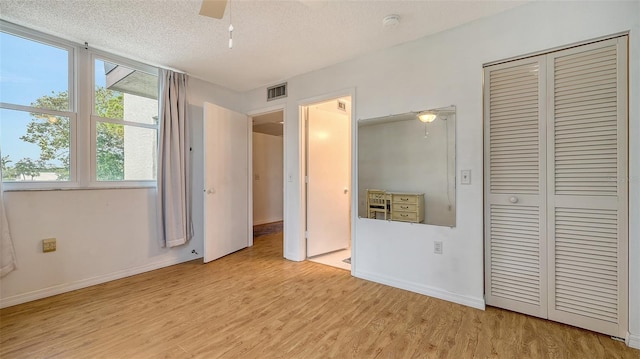 unfurnished bedroom with ceiling fan, light hardwood / wood-style floors, and a textured ceiling