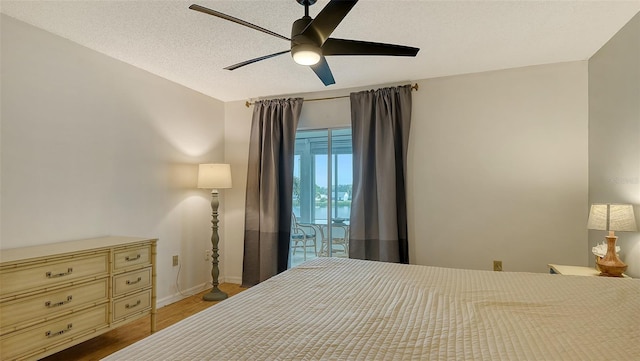 bedroom with ceiling fan, light hardwood / wood-style floors, and a textured ceiling