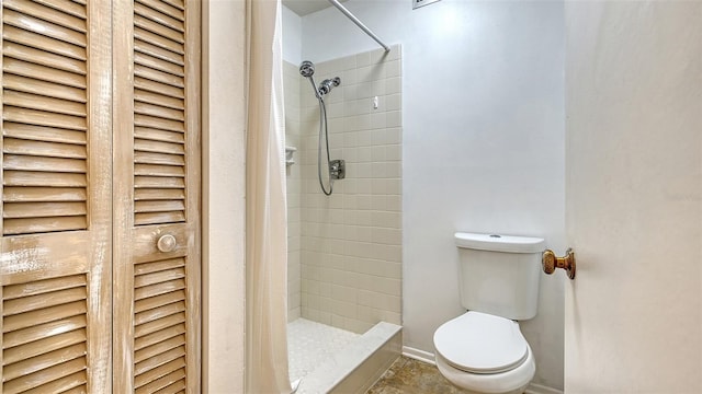 bathroom featuring tiled shower and toilet