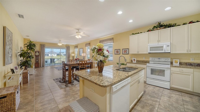 kitchen with light tile patterned flooring, white appliances, a center island with sink, and sink