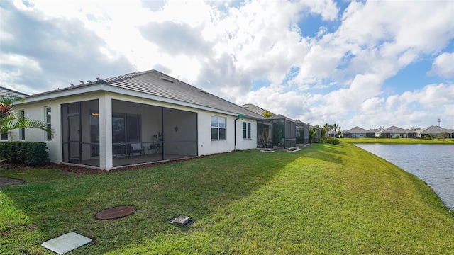 rear view of house featuring a sunroom, a water view, and a lawn