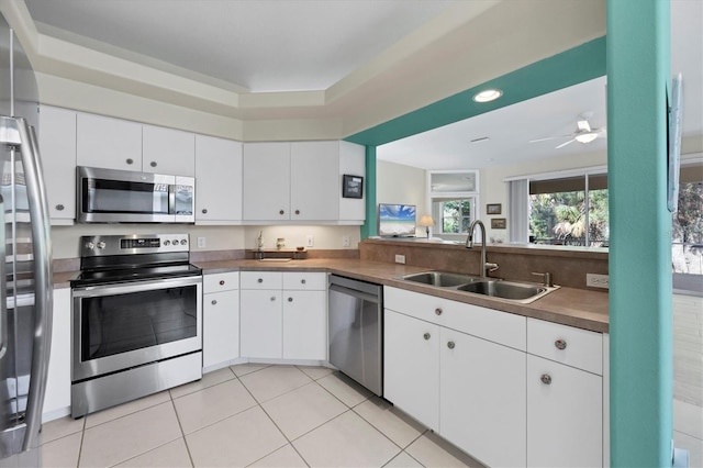 kitchen featuring white cabinets, light tile patterned floors, stainless steel appliances, and sink