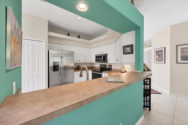 kitchen with white cabinetry, sink, stainless steel appliances, kitchen peninsula, and light tile patterned floors