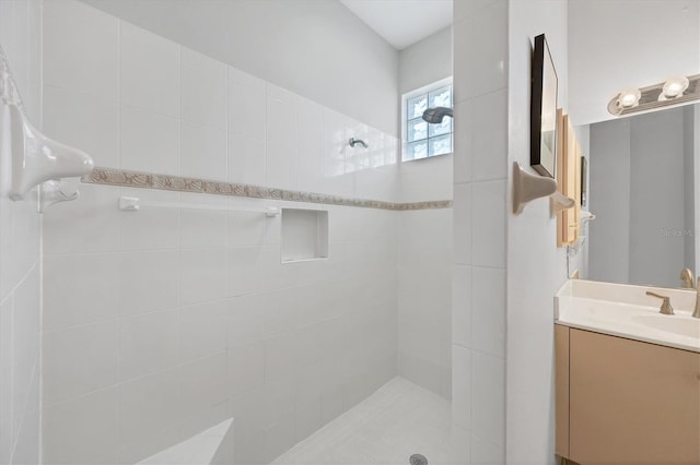 bathroom with a tile shower and vanity