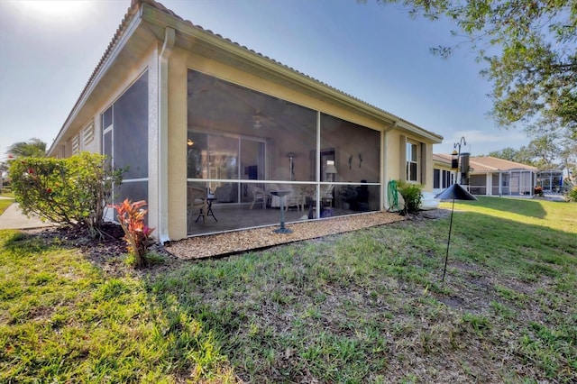 rear view of property featuring a lawn and a sunroom