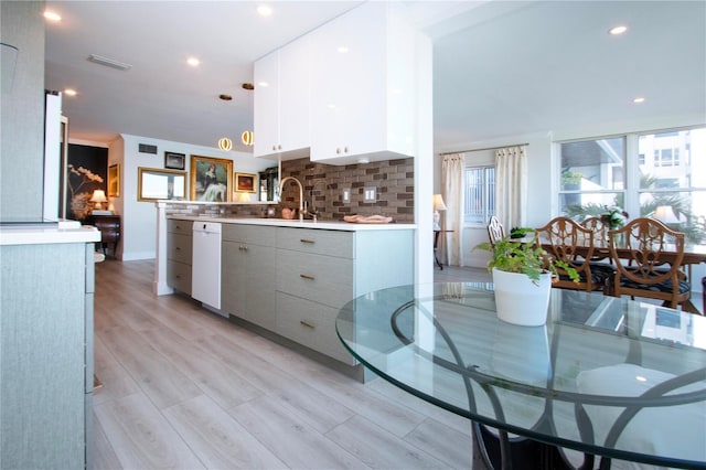 kitchen with decorative backsplash, pendant lighting, dishwasher, light hardwood / wood-style floors, and white cabinetry