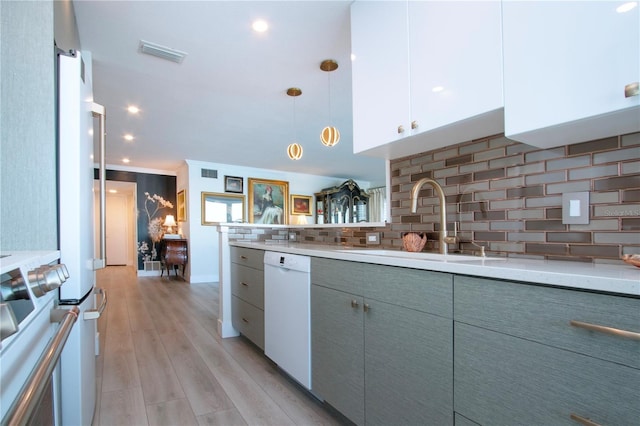 kitchen with light wood-type flooring, tasteful backsplash, sink, decorative light fixtures, and dishwasher