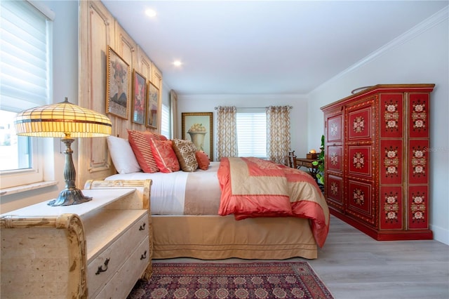 bedroom with multiple windows, light hardwood / wood-style flooring, and ornamental molding