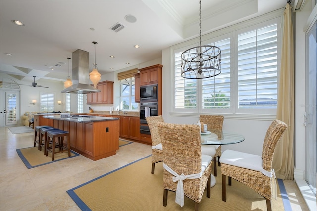 dining area with ceiling fan with notable chandelier, ornamental molding, and sink