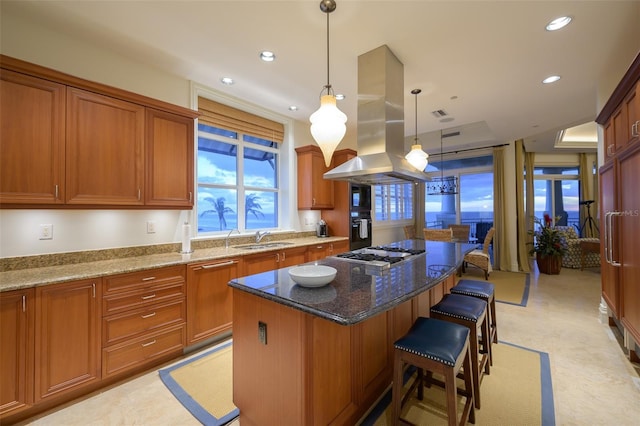 kitchen with a breakfast bar area, decorative light fixtures, a kitchen island, island exhaust hood, and stainless steel gas cooktop