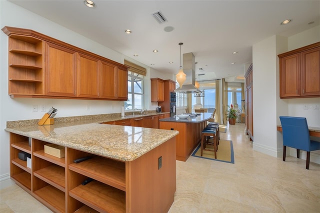 kitchen with kitchen peninsula, island exhaust hood, a breakfast bar, a kitchen island, and hanging light fixtures