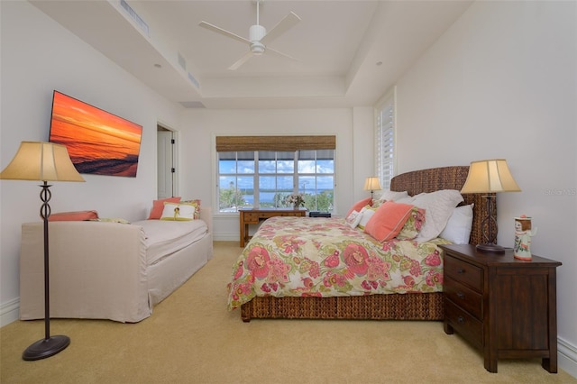 carpeted bedroom featuring ceiling fan and a raised ceiling