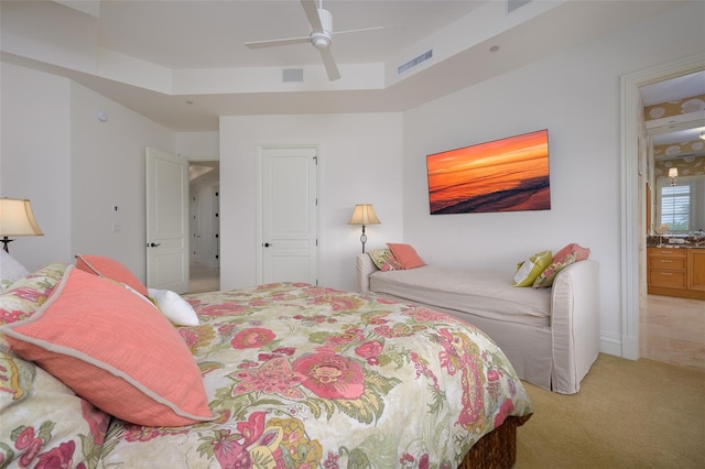 carpeted bedroom with ceiling fan and a raised ceiling