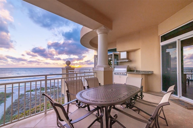 balcony at dusk with a grill, a water view, a beach view, and sink