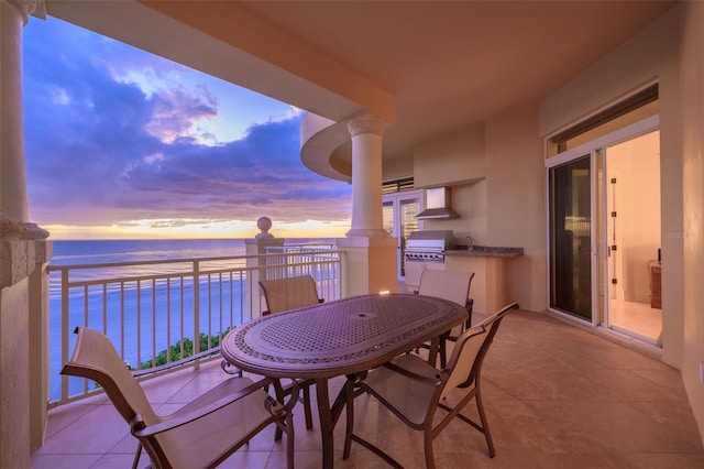 balcony at dusk featuring a view of the beach, a water view, and area for grilling