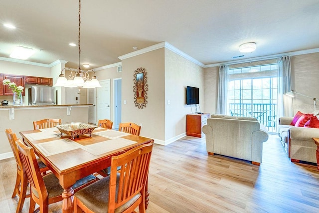 dining area with a notable chandelier, crown molding, and light hardwood / wood-style flooring