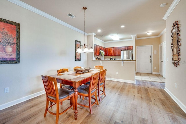 dining area featuring light hardwood / wood-style floors, crown molding, and an inviting chandelier