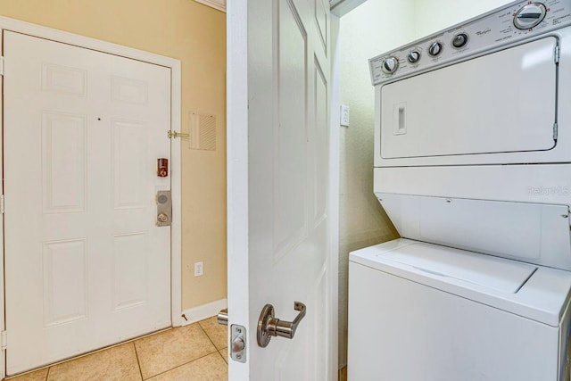 laundry area with stacked washer and dryer and light tile patterned flooring