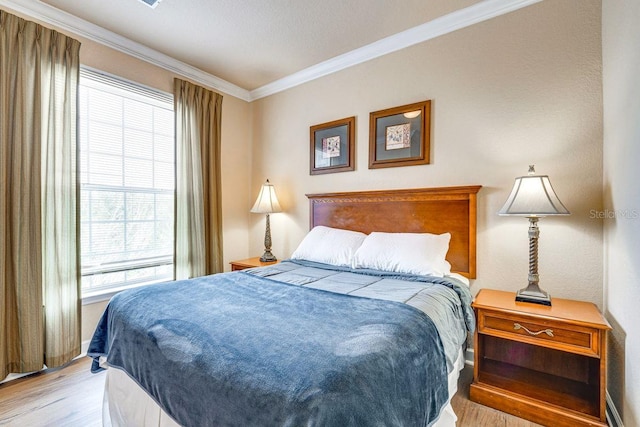 bedroom featuring ornamental molding and light hardwood / wood-style flooring