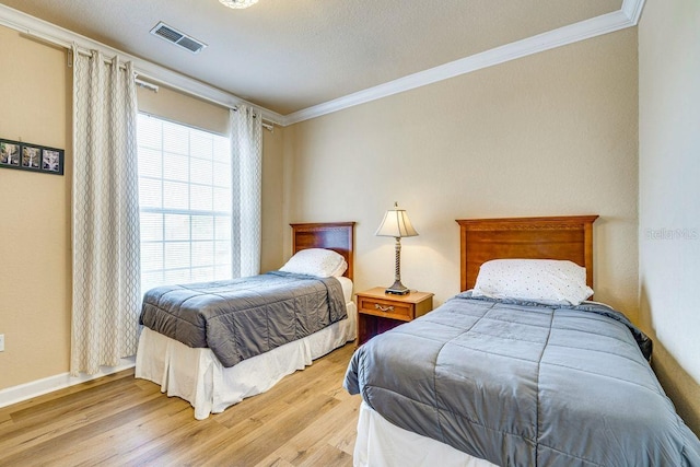 bedroom with crown molding, light hardwood / wood-style floors, and a textured ceiling