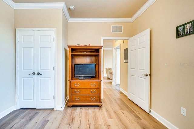 unfurnished bedroom with a closet, light hardwood / wood-style floors, a textured ceiling, and ornamental molding