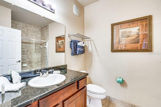 bathroom featuring toilet, vanity, tile patterned floors, and a shower with shower door