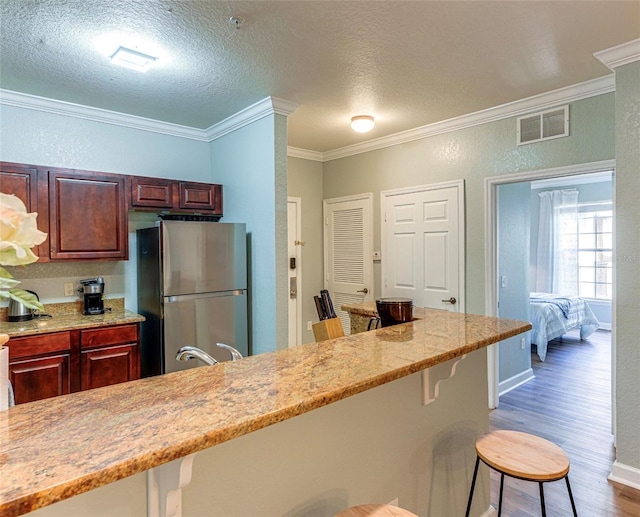 1301 Tuscan Ter Unit 9401, Davenport, FL 33896 - kitchen featuring freestanding refrigerator, a kitchen bar, crown molding, wood finished floors, and light stone countertops