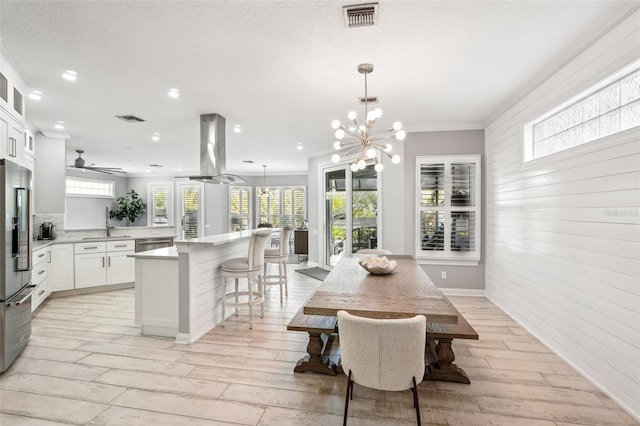 dining area featuring ceiling fan with notable chandelier, light hardwood / wood-style flooring, crown molding, and sink