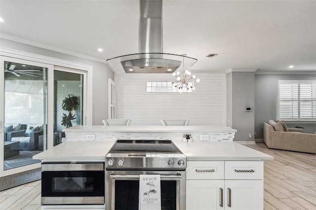 kitchen featuring electric range, light hardwood / wood-style flooring, island exhaust hood, white cabinets, and ornamental molding