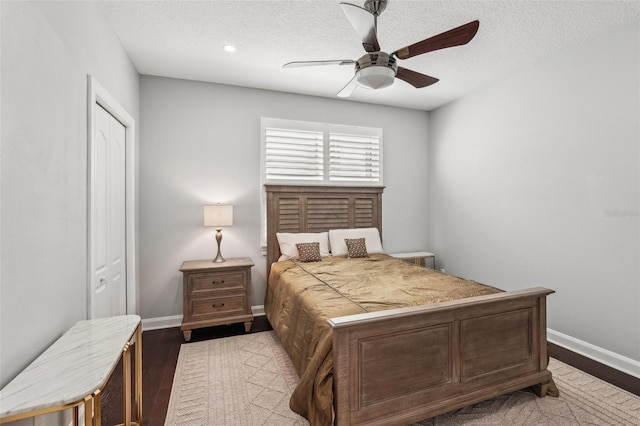 bedroom with hardwood / wood-style floors, ceiling fan, a textured ceiling, and a closet