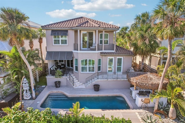 rear view of house with area for grilling, a patio area, a balcony, and exterior bar