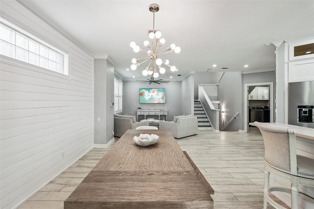 dining space featuring wooden walls, ornamental molding, a chandelier, and light hardwood / wood-style floors