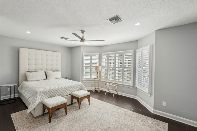 bedroom featuring ceiling fan, dark hardwood / wood-style flooring, and a textured ceiling